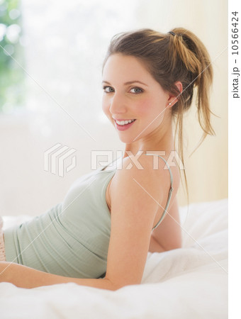 Portrait of young woman lying on bed in bedroom Portrait of young woman lying on bed in bedroom 10566424