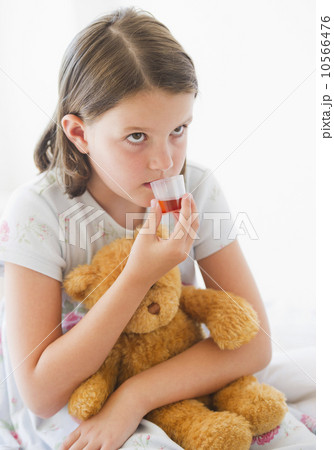 Close up of sick girl (6-7) with teddy bear drinking medicament Close up of sick girl (6-7) with teddy bear drinking medicament 10566476
