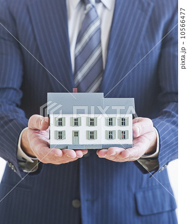 Man wearing suit holding small house model Man wearing suit holding small house model 10566477