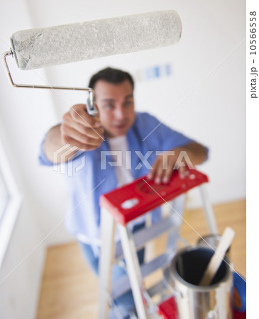 Man standing on ladder with paint roller 10566558