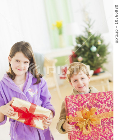 Girl (8-9) and boy (6-7) holding christmas gifts Girl (8-9) and boy (6-7) holding christmas gifts 10566980