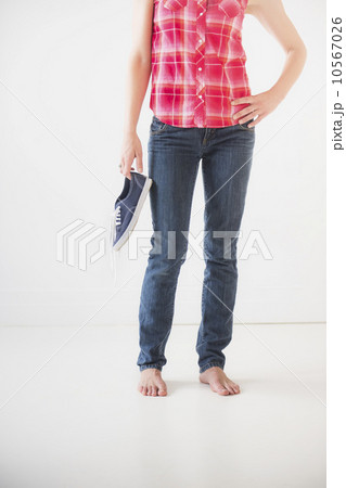 Studio shot of young barefoot woman holding shoes, low section 10567026