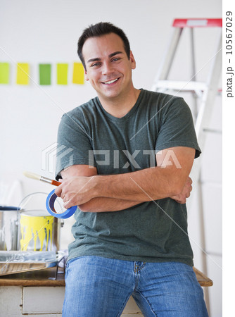 Portrait of man with arms folded with painting equipment behind him 10567029