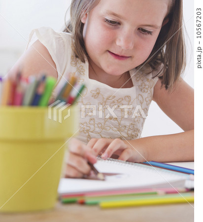 Close up of girl (6-7) drawing in notebook 10567203