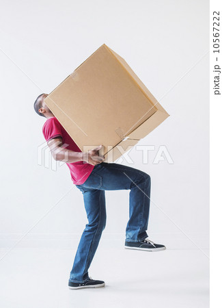 Studio shot of young man with large cardboard box Studio shot of young man with large cardboard box 10567222
