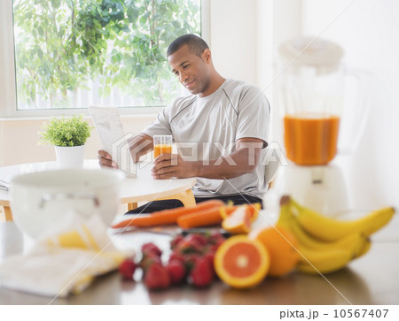 Young man sitting in kitchen and drinking juice 10567407