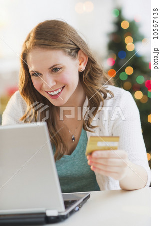 Young woman on-line shopping from home with Christmas tree on background 10567438