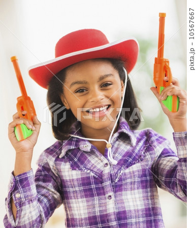 Portrait of smiling girl (6-7) with cowboy hat and toy gun Portrait of smiling girl (6-7) with cowboy hat and toy gun 10567667