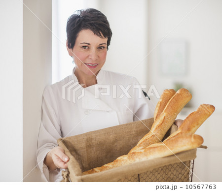 Portrait of mature woman holding basket with baguettes 10567763