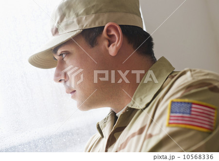 Man wearing military uniform looking through window 10568336