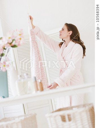 Young woman holding dress in bedroom 10568394