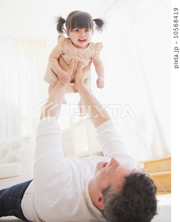 Father lifting baby daughter (12-17 months) while lying on carpet Father lifting baby daughter (12-17 months) while lying on carpet 10568419