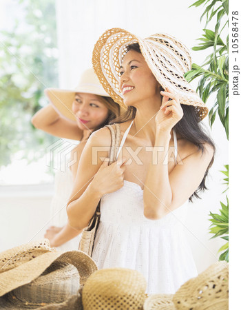 Two women trying on straw hat 10568478