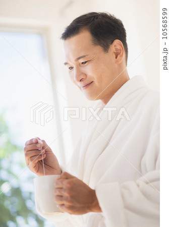 Mid adult man mixing herbal tea Mid adult man mixing herbal tea 10568599