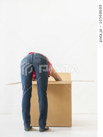 Studio shot of young woman looking into box Studio shot of young woman looking into box 10568699