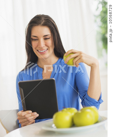 Portrait of woman eating apple and using digital tablet Portrait of woman eating apple and using digital tablet 10568729