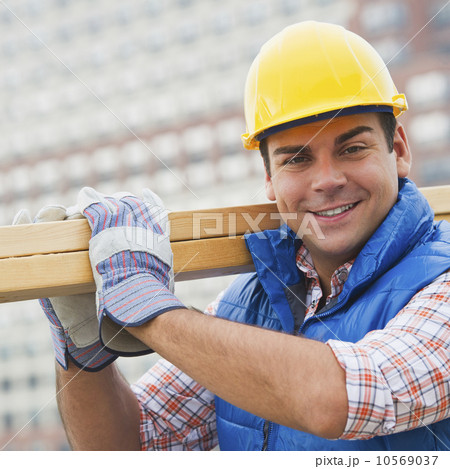 Construction worker carrying planks on construction site 10569037