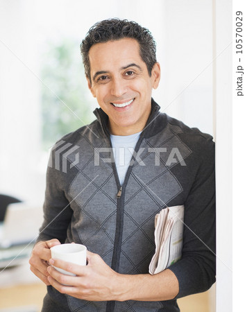 Portrait of man holding newspaper and coffee mug Portrait of man holding newspaper and coffee mug 10570029