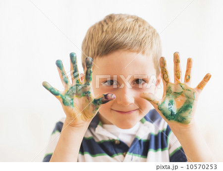 Young boy (6-7) showing hands stained with paint 10570253