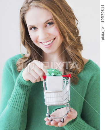 Young woman holding miniature shopping cart with gift box 10570311