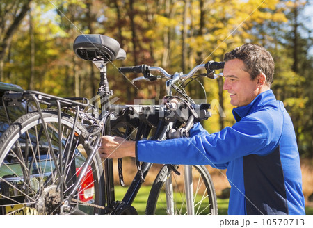 Man putting bicycle onto bike rack Man putting bicycle onto bike rack 10570713