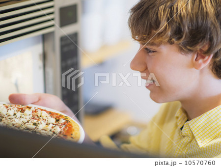 Teenage boy (14-15) preparing pizza 10570760