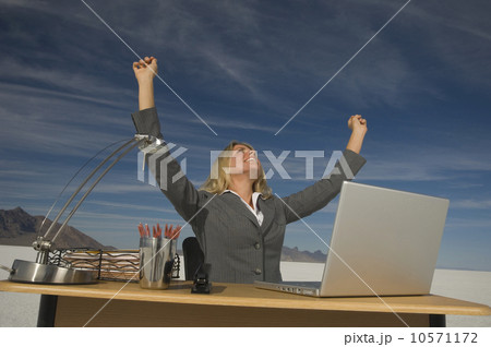 Businesswoman cheering at desk, Salt Flats, Utah, United States Businesswoman cheering at desk, Salt Flats, Utah, United States 10571172