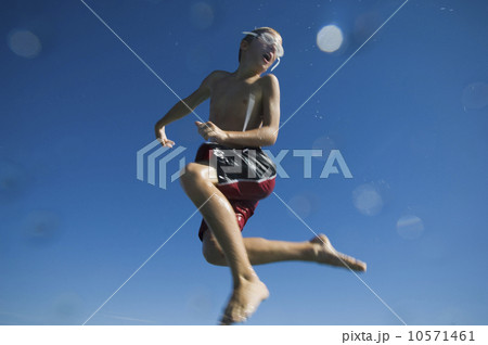 Boy in bathing suit jumping in air, Utah, United States 10571461