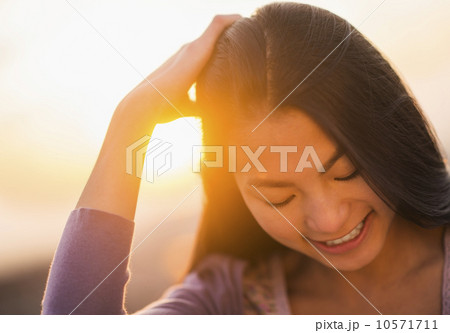 Close-up of smiling teenage girl ( 16-17 years) with sunset in background 10571711