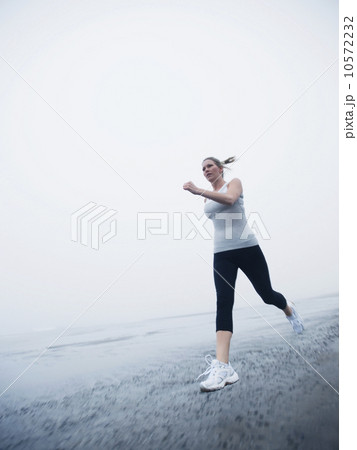 Woman jogging on foggy beach 10572232