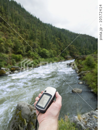 Man holding gps unit by river 10572414
