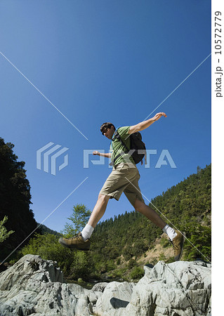 Hiker jumping across rocks 10572779