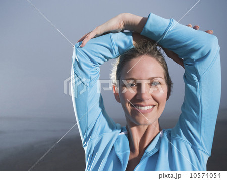 Close up of woman with hands overhead on foggy beach 10574054