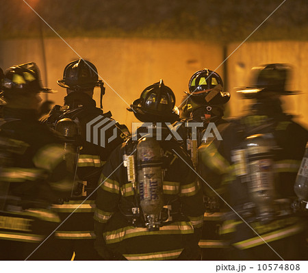 Firefighters standing outside burning building Firefighters standing outside burning building 10574808