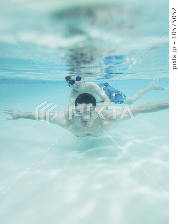 Boy swimming on father’s back underwater 10575052