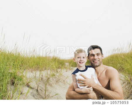Portrait of father and son hugging on beach 10575053