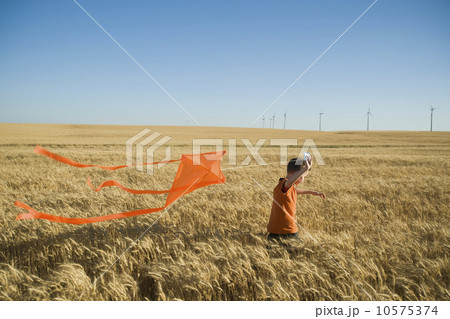 Boy running with kite on wind farm Boy running with kite on wind farm 10575374