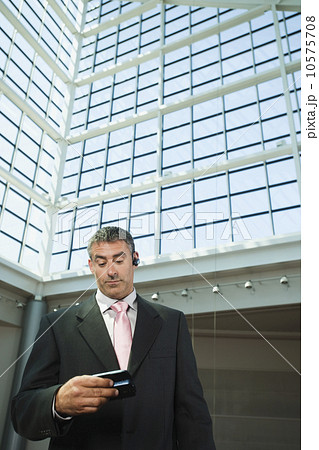 Businessman looking at cell phone in convention center atrium Businessman looking at cell phone in convention center atrium 10575708