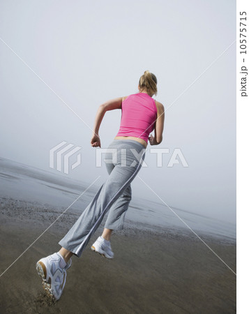 Woman jogging on foggy beach Woman jogging on foggy beach 10575715