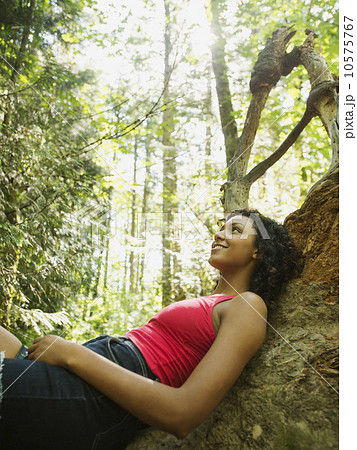 Young woman sitting on log in forest Young woman sitting on log in forest 10575767