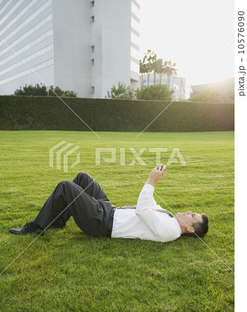 Businessman texting while lying on grass 10576090