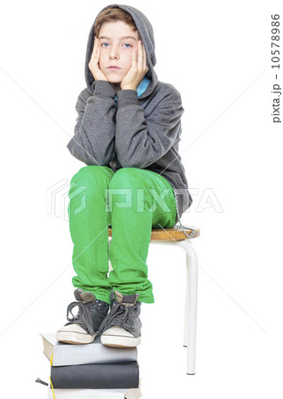 teenager boy sitting on a stool with his feet on a stack of book 10578986