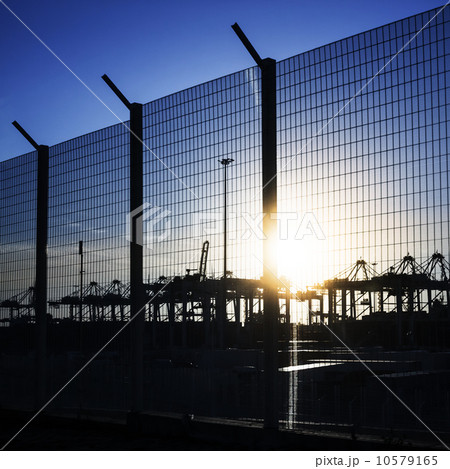 Port area fence with silhouettes of container cranes in the sunl Port area fence with silhouettes of container cranes in the sunl 10579165