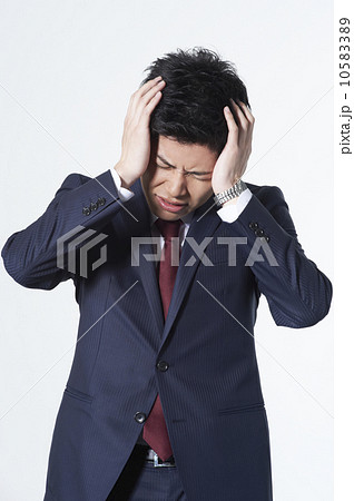 頭を抱えるスーツの男性の写真素材 1053