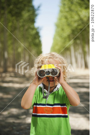 Boy (2-3) looking through binoculars in tree farm Boy (2-3) looking through binoculars in tree farm 10622870