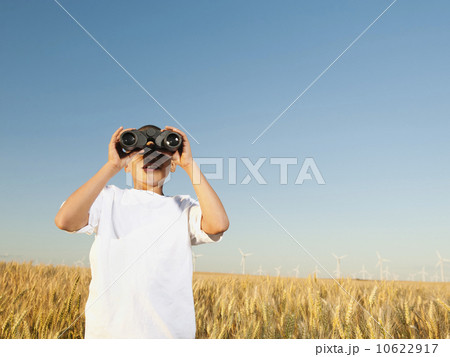 Boy (8-9) standing in wheat field, looking through binoculars Boy (8-9) standing in wheat field, looking through binoculars 10622917