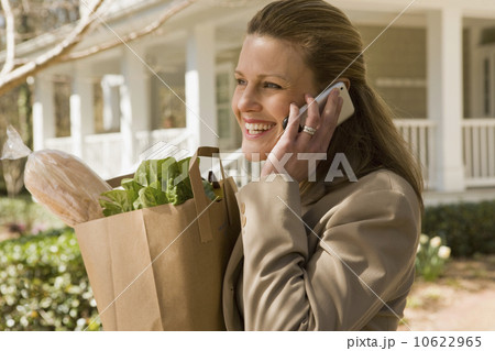 Woman carrying groceries and talking on telephone 10622965