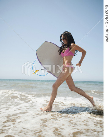 Young attractive woman running into water with swimming boards 10623048