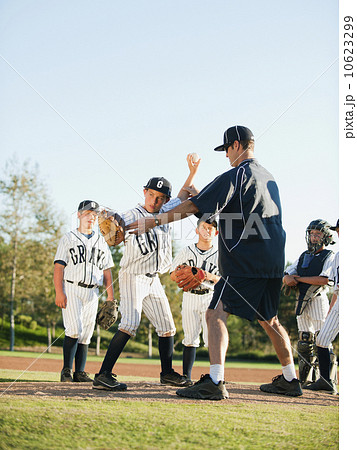 Baseball coach and boys (10-11) standing on baseball diamond Baseball coach and boys (10-11) standing on baseball diamond 10623299