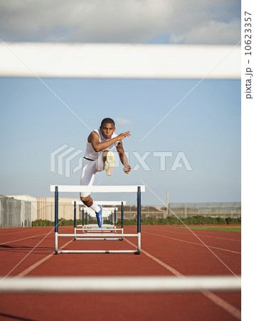 Boy (12-13) hurdling on running track 10623357